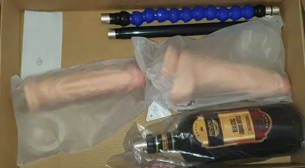 W pudełku leży maszyna erotyczna: dwa realistyczne falusy, butelka imitująca alkohol i dwa giętkie wężyki.