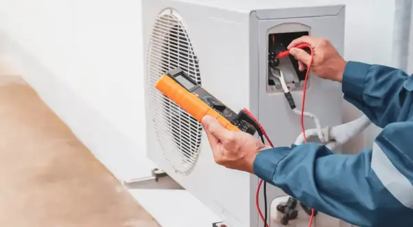 Un technicien vérifie une pompe à chaleur, une solution moderne pour remplacer le chauffage électrique.