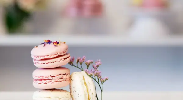 En stapel rosa och vita macarons, dekorerade med blommor. Perfekt för ett macarons recept.