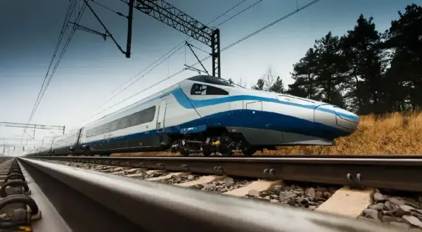 Pendolino pędzi po torach, a pytanie "ile jedzie pendolino" pozostaje otwarte. Pociąg w biało-niebieskich barwach mija suchą trawę i drzewa.