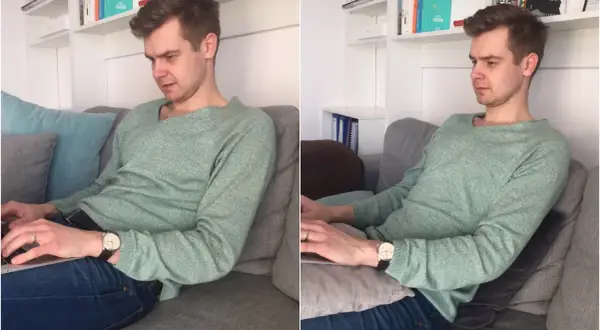Mężczyzna w swetrze siedzi w **pozycji półleżącej** na kanapie, pracując na laptopie.