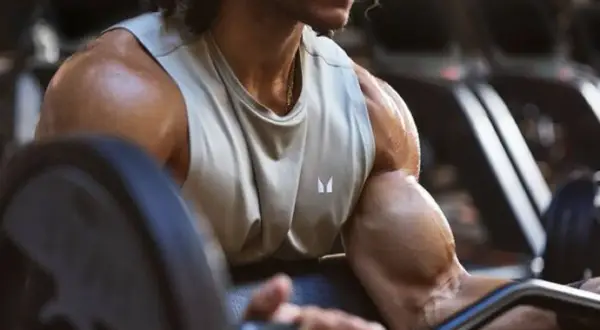 Mann im Fitnessstudio trainiert Bizeps, um dicke Arme zu bekommen.