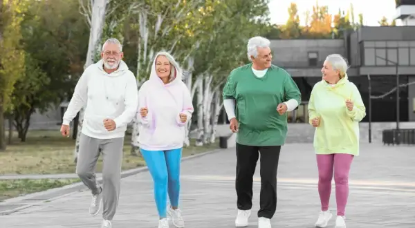 Quatre seniors souriants font du jogging en plein air, une belle illustration des activités pour préparer sa retraite.
