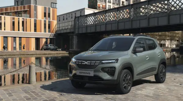 Dacia Spring Electric, miejski samochód elektryczny, zaparkowany nad kanałem w słoneczny dzień.