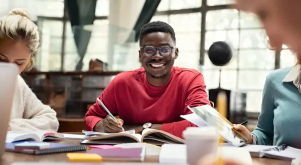 Jóvenes sonrientes estudiando juntos, una experiencia que inspira a estudiar en el extranjero.