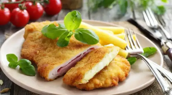 Schab po szwajcarsku, panierowany kotlet z szynką i serem, podany z makaronem i bazylią.