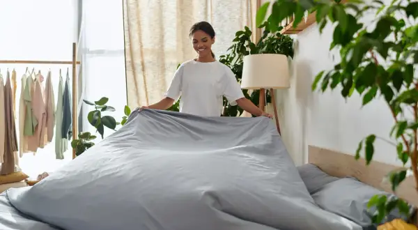 Frau richtet Bettwäsche, die nicht einlaufen kann, da sie aus Polyester ist.
