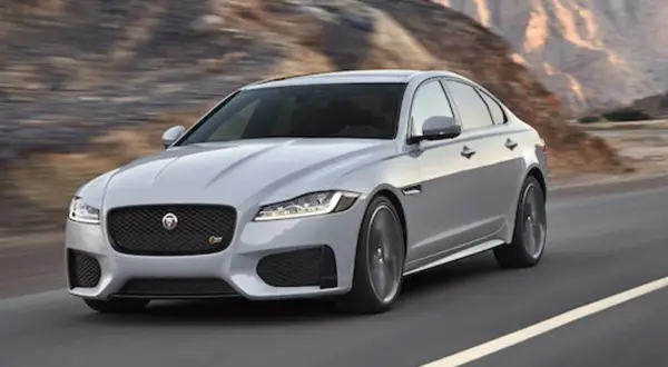 Srebrny Jaguar XF pędzi po pustynnej drodze. Czy jaguar xf jest drogi w utrzymaniu? To pytanie zadaje sobie wielu miłośników tej marki.