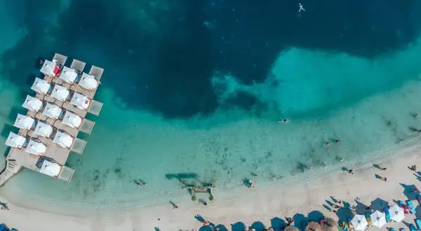 En strand med turkost vatten och solstolar, som påminner om Europas Maldiverna i Albanien.