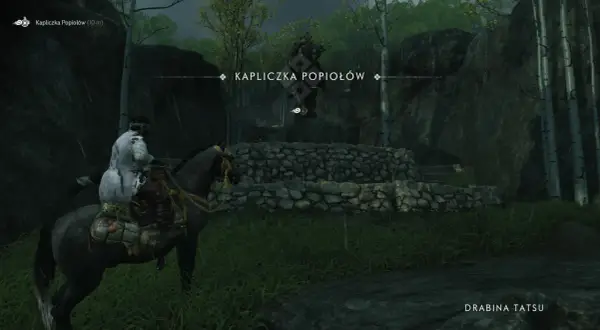 Samuraj na koniu zbliża się do Kapliczki Popiołów, ukrytej wśród drzew i skał.