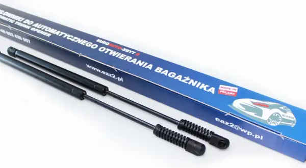 Dwa siłowniki do automatycznego otwierania bagażnika, zapakowane w niebieskie pudełko z napisem "MADE IN POLAND".