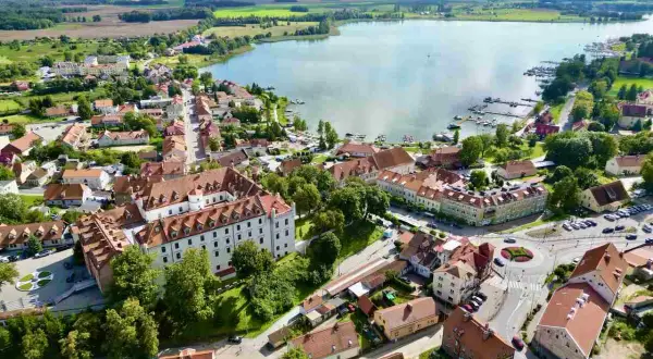Idealne miejsce, gdzie na Mazury we dwoje: urokliwe miasteczko z zamkiem, jezioro z przystanią i zielone pola.