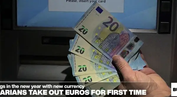 Ręka trzyma banknoty 20 euro przy bankomacie. Bułgarzy po raz pierwszy wypłacają nową walutę.