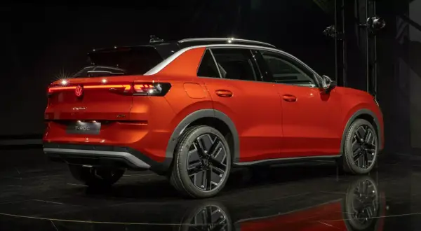 Pomarańczowy Volkswagen T-Roc z czarnym dachem, stylowymi felgami i nowoczesnymi światłami. Sprawdź aktualną volkswagen t-roc cena.