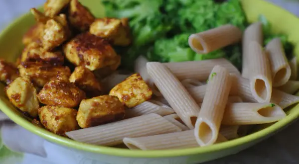 Szybkie przepisy na dania w 15 minut: kurczak w przyprawach, makaron penne i brokuły na talerzu.