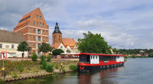 Statek "Hoffnung" cumuje przy brzegu rzeki Łaby w Niemczech, obok zabytkowych budynków i kościoła.