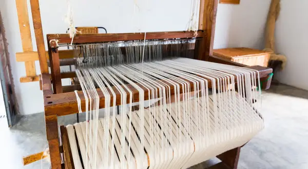 Telai in legno con fili bianchi pronti per creare tessuti come quelli del Medioevo.
