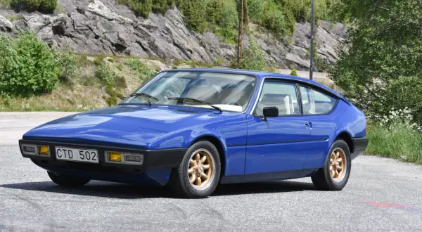Blå Matra Bagheera sportbil parkerad vid en bergssluttning med grönska.