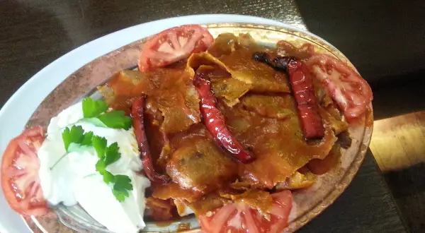 Iskender kebab z sosem pomidorowym, jogurtem, papryczkami i pomidorami.