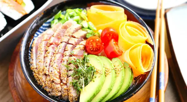 Ein bunter Chirashi Bowl mit Thunfisch, Avocado, Tomaten und Karottenröllchen.