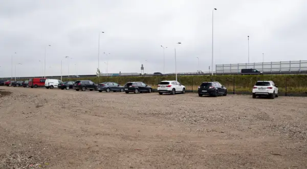 Rząd samochodów na parkingu, w tym czerwony van i białe SUV-y. Zastanawiasz się, ile kosztuje parking na lotnisku w Warszawie?