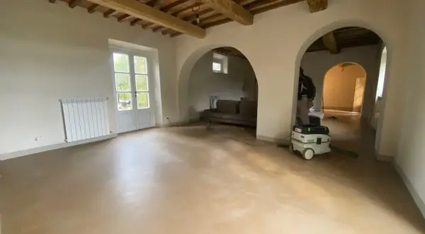 Interno con soffitto a travi, pareti in tinteggiatura a calce e un aspiratore professionale pronto per la pulizia.