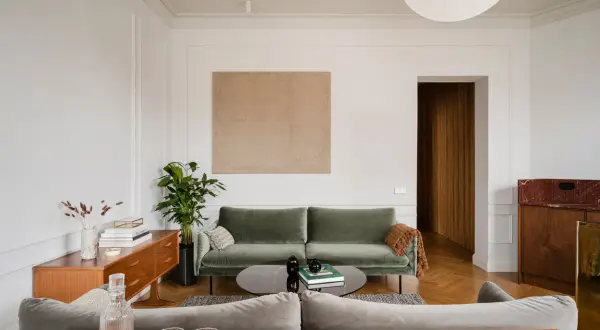Disposizione divani salotto: un divano verde salvia e uno grigio creano un angolo conversazione accogliente, con un tavolino basso e un mobile vintage.