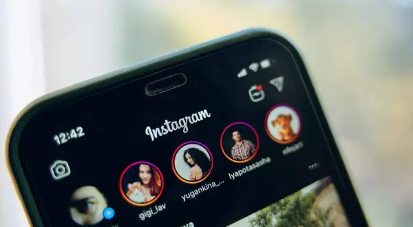 Telefon z otwartym Instagramem, pokazujący profile znajomych. Dowiedz się, jak udostępnić czyjąś relację na swoim IG.