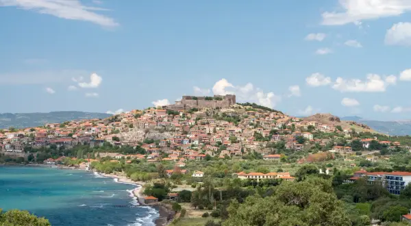 Widok na malowniczą wioskę z zamkiem na wzgórzu, turkusowe morze i zielone wzgórza. Lesbos atrakcje zachwycają!