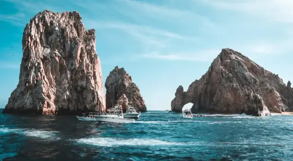 Łodzie koło skalnych formacji w Cabo San Lucas. Zastanawiasz się, ile trwa lot do Meksyku?