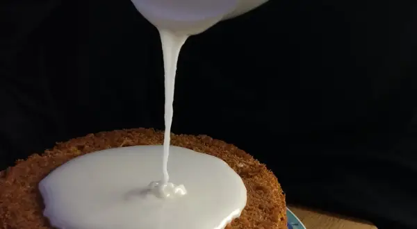 Ein cremiger zuckerguss mit milch fließt auf einen Kuchen.