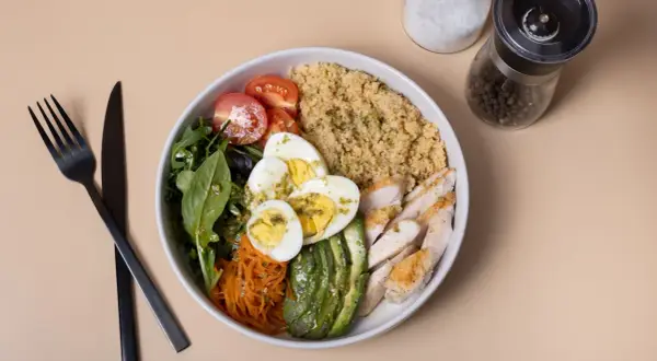 Une salade composée excellente avec poulet grillé, œufs durs, avocat, tomates cerises, carottes râpées et quinoa.