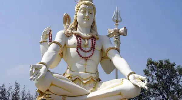 Stor staty av Shiva, en viktig gudom inom hinduismen, sitter i meditation med en orm runt halsen och en treudd i handen.