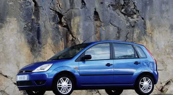 Niebieski Ford Fiesta MK5 zaparkowany przy skalnej ścianie.