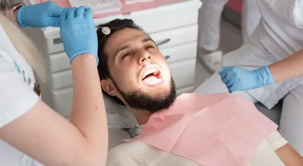 Pacjent u dentysty, który bada zęby. Może to być próchnica pod plombą, która wymaga uwagi.