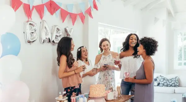 Radosne kobiety świętują baby shower. Balony z napisem "BABY", girlandy i tort tworzą atmosferę. To idealne miejsce, by dowiedzieć się, baby shower co to jest!