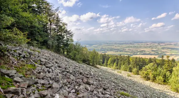 Kamieniste zbocze Gór Świętokrzyskich z widokiem na dolinę i lasy.