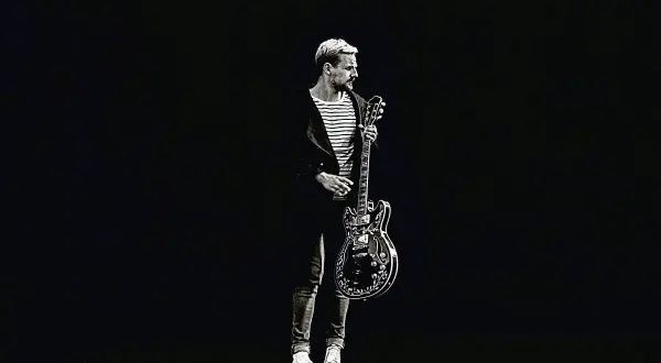 Paweł Domagała z gitarą, jakby gotowy do wykonania utworu "Weź nie pytaj".