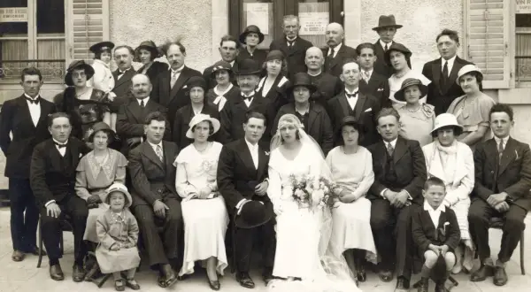 Un groupe de personnes pose pour une photo de mariage. La mariée est au centre, entourée de sa famille et de ses amis. Ce **registre mariage** témoigne d'un jour heureux.