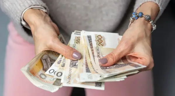 Dłonie trzymające plik banknotów 200 zł. To może być wypłata, oszczędności, a może nawet słynne "kosiniakowe".