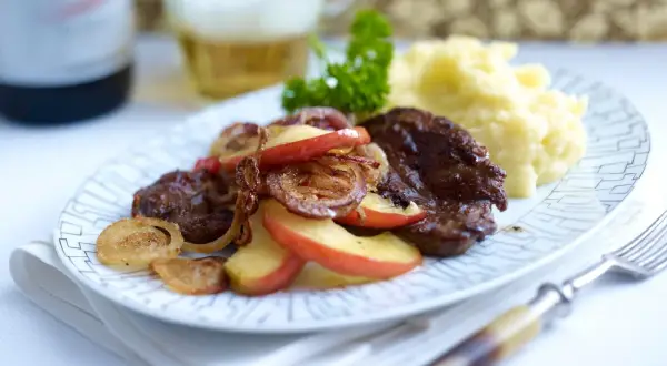 Herzhaft gebratene leber mit zwiebeln und apfel, dazu Kartoffelpüree und ein Bier.