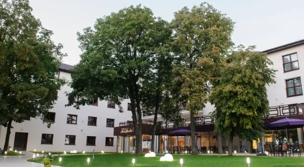 Nowoczesny budynek Teodorka Med & Spa otoczony zielenią i oświetlony lampkami.