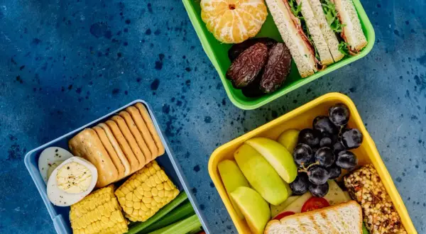 Czy warto kupić catering dietetyczny od najpopularniejszej trenerki fitness? Trzy pudełka pełne zdrowych przekąsek: kanapki, owoce, warzywa, jajka, krakersy.