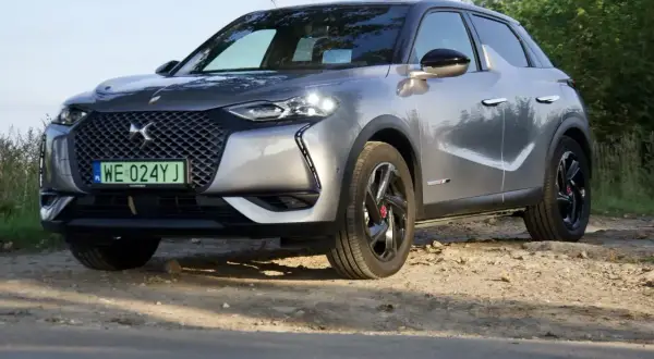 Srebrny DS3 Crossback na drodze gruntowej, z zieloną tablicą rejestracyjną.