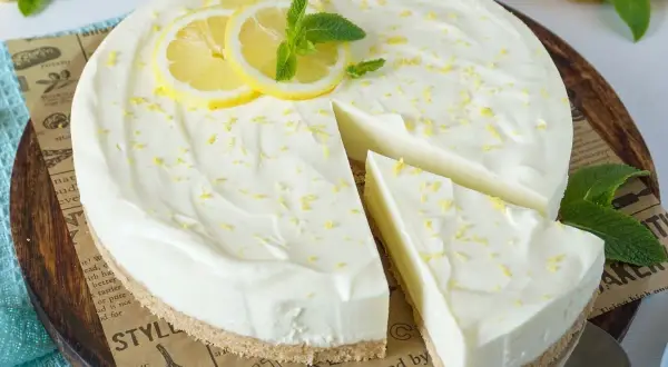 Cremige Philadelphia Torte mit Zitronenscheiben und Minze, ein Stück wurde bereits angeschnitten.