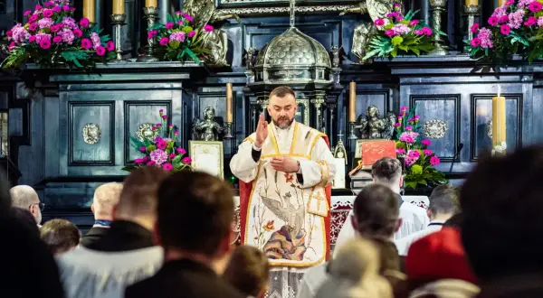 Ksiądz odprawia mszę gregoriańską. Kiedy zamawiać? W kościele, wśród wiernych, przy ołtarzu ozdobionym kwiatami i świecami.