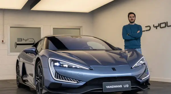 Hombre posa junto al deportivo BYD Yangwang U9, con diseño futurista y luces LED llamativas.