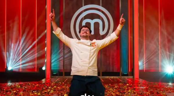 Vincitore del finale MasterChef 2026 in ginocchio tra coriandoli dorati, con le braccia alzate e il logo di MasterChef sullo sfondo.