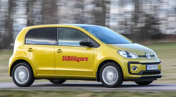 Gul Volkswagen Up körs på en väg, med texten "ViBilägare" på sidan. En potentiell vw up problem kan vara att den är för liten för familjen.