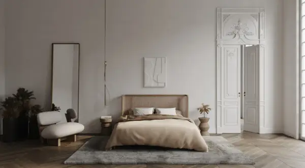 Elegancka sypialnia z łóżkiem z rattanowym zagłówkiem, dywanem i ozdobnymi drzwiami z bogatą sztukaterią w sypialni.